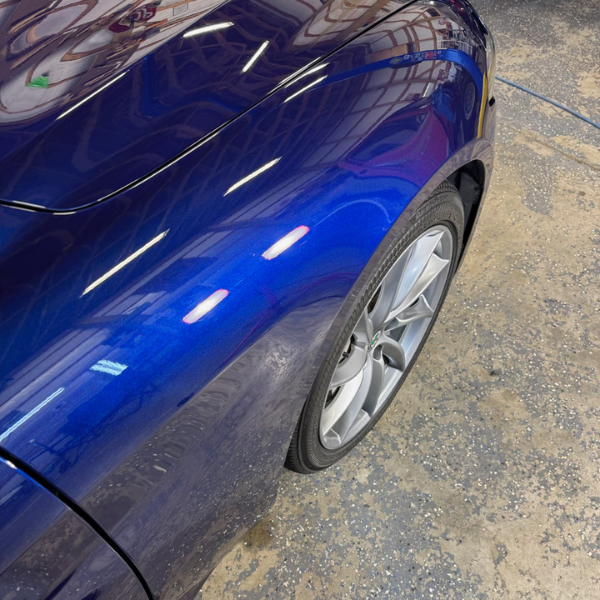 The front passenger side of a deep blue car after an exterior shine package detailing the car. | Mystic AC Detailing